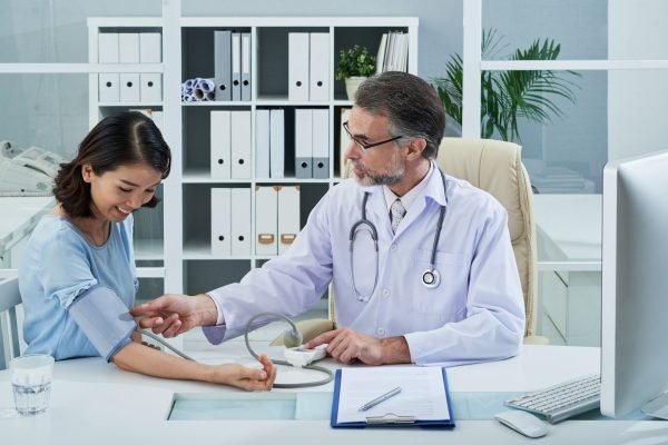 Mature doctor checking blood pressure of female patient